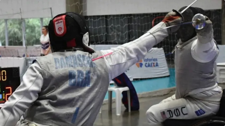 Two fencers in action during a match, one wearing a 'BRA' jersey and the other with a 'USA' jersey.