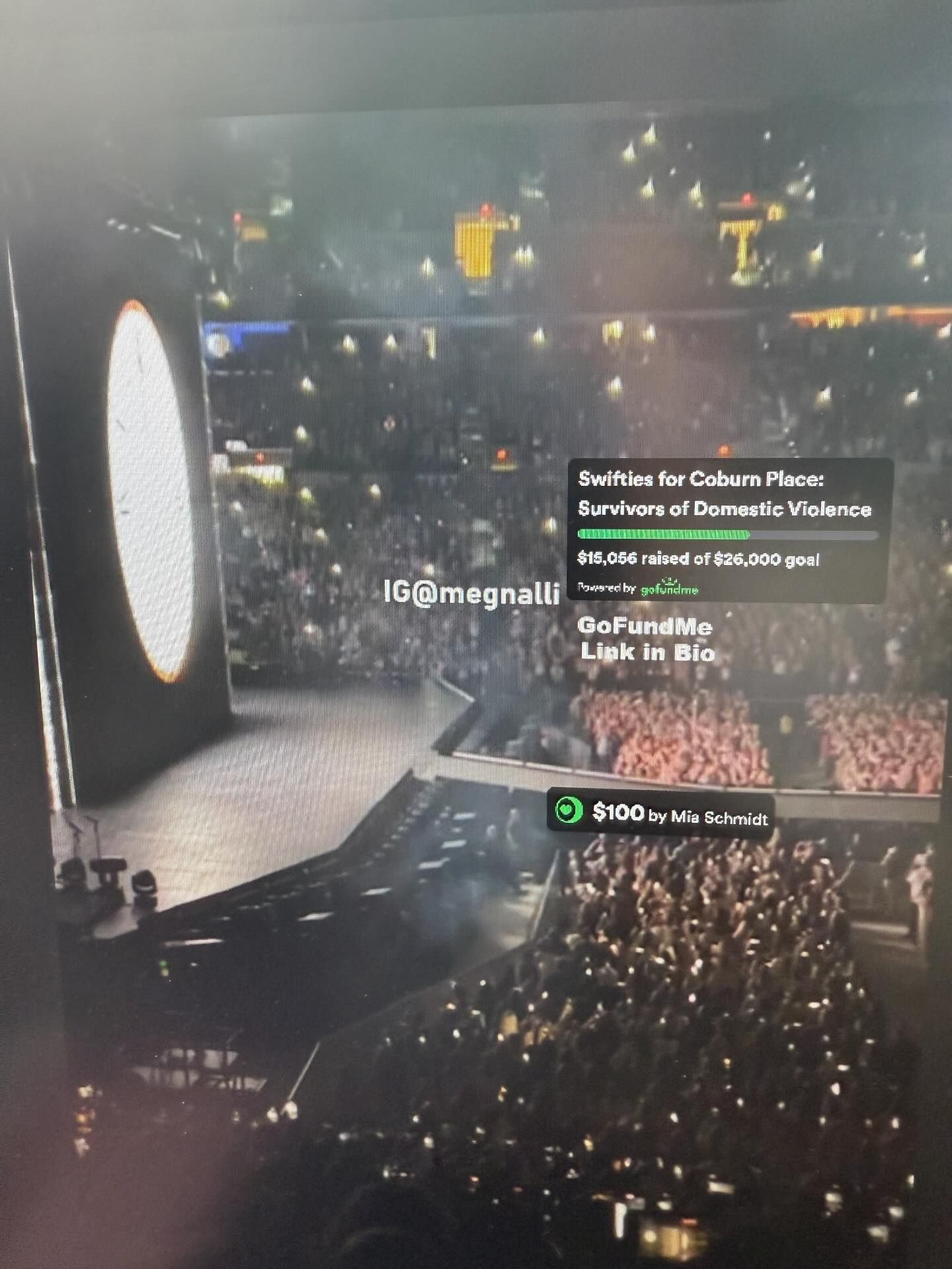 A concert crowd with a GoFundMe campaign banner for 'Swifties for Coburn Place: Survivors of Domestic Violence,' showing the amount raised and a donation of $100 from Mia Schmidt.