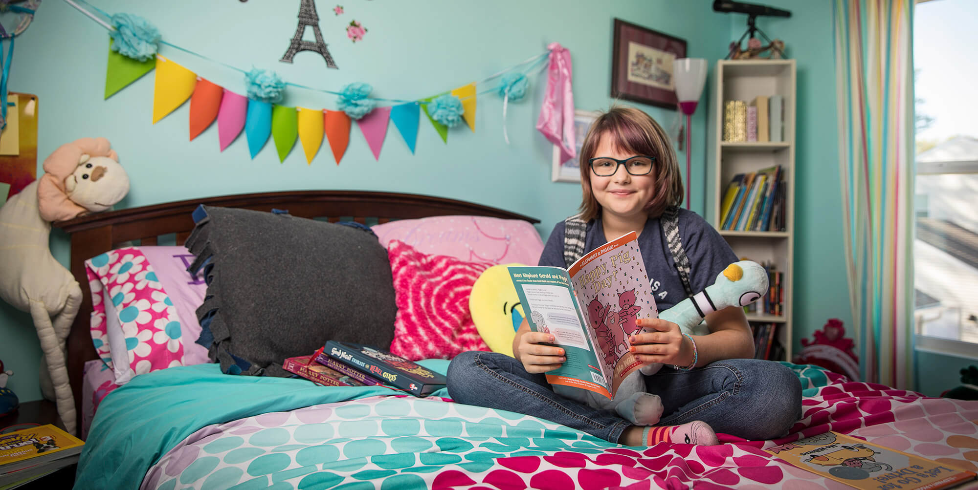 Girl sitting on a bed smiling and holding a book