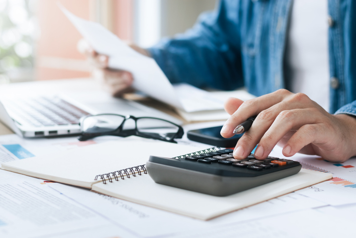 Person filling out forms and using a calculator.