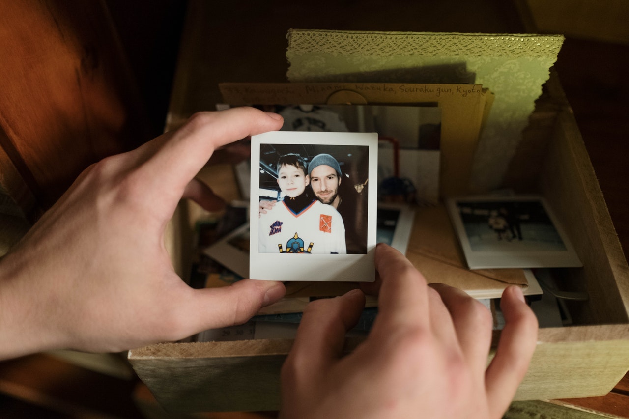 hands holding a small photograph of two friends cheek to cheek