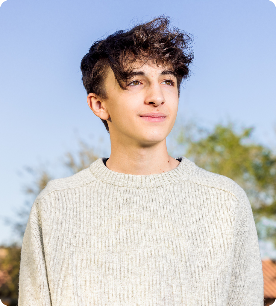 young man brunette hair with grey sweater standing outside