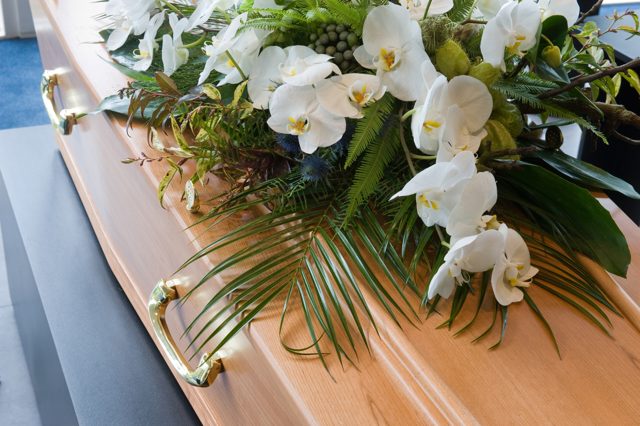 a coffin with beautiful white funeral flowers to honor a loved one who has passed